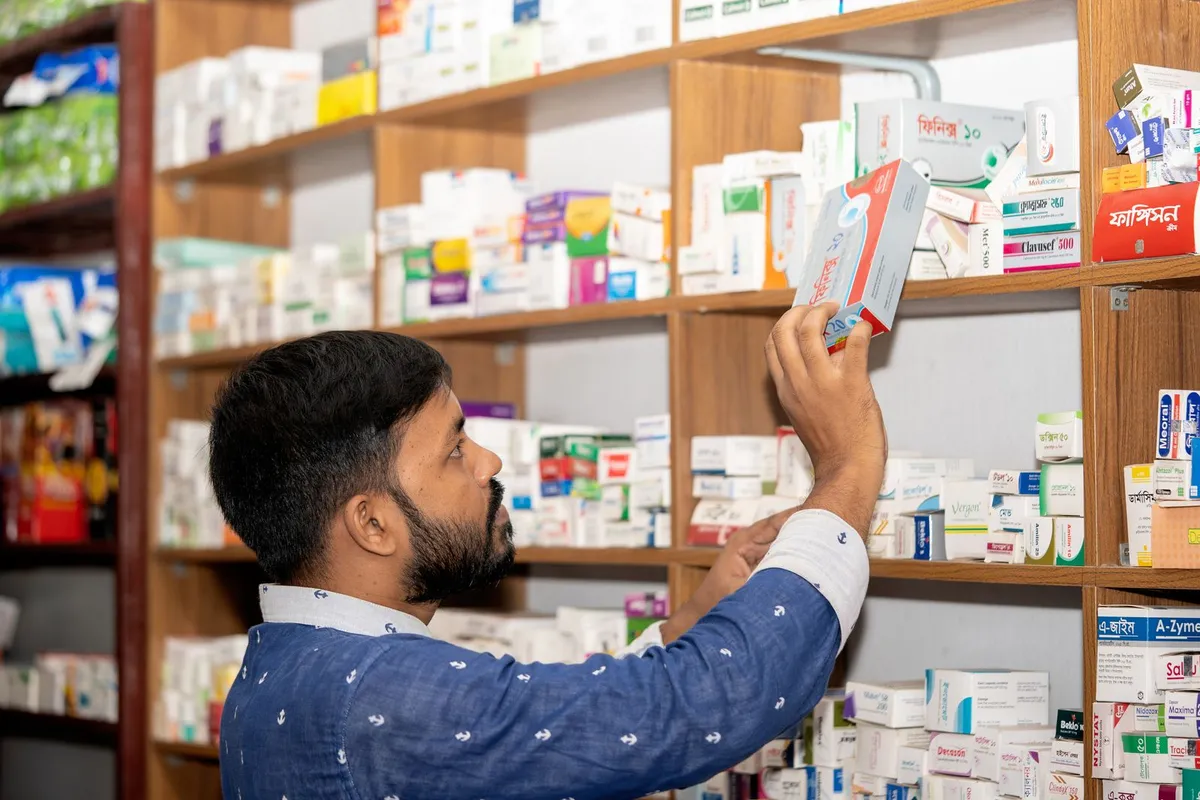 Apotheker sortiert Packungen im Regal einer Apotheke